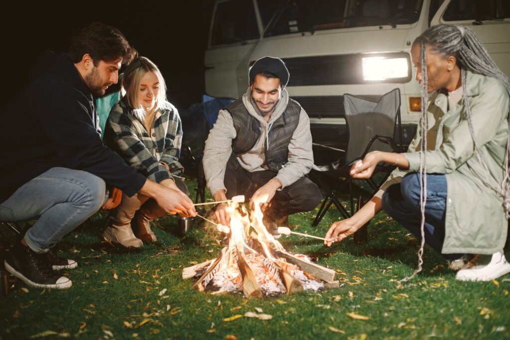 Ragazzi arrostiscono marshmallow attorno al fuoco da campo