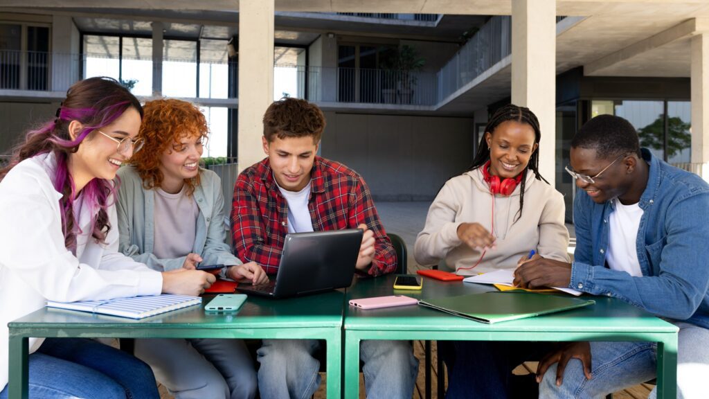 Studente con cuffie e laptop cammina nel campus universitario