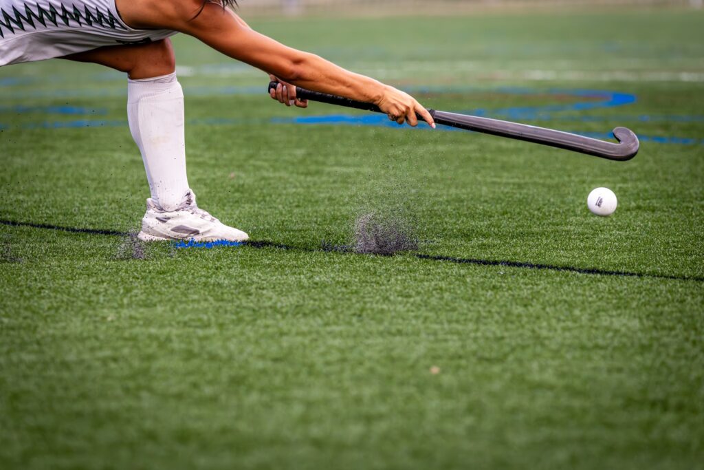 Giocatrice di hockey su prato colpisce la palla sul campo in erba sintetica