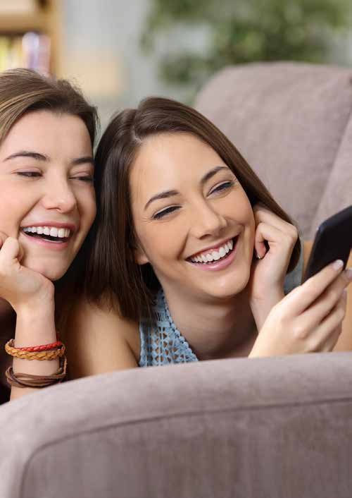 Due amiche ridono sul divano di casa